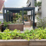Der Blick über den Gemüsegarten - komplett mit Hochbeeten gestaltet zum Sitzplatz mit der Pergola