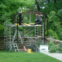 Herr Gräf bei der Arbeit. Hier wird ein Pavillon von dem Schmied aufgestellt, der zur Hälfte auf der Natursteinmauer steht.