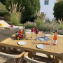Gedeckter Tisch aus Holz, im Hintergrund ein Staudenbeet