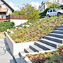 Der Treppe mit ihrem neuen Belag sieht man nicht an, dass das Fundament erhalten blieb; das Gelände wird vor dem Gebäude durch eine Mauer abgefangen, so dass noch ein breiter Zugang zur Terrasse möglich ist. Der Handlauf an der Treppe fehlt noch.
