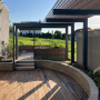 Neben der Holzterrasse aus Thermoesche ist die Pergola aus Stahl mit Holzauflagen das prägende Element